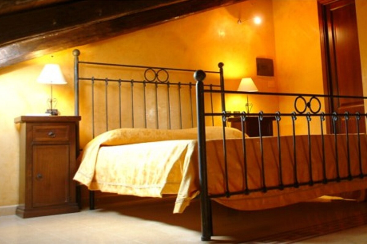 Ein Schlafzimmer mit einem Metallbettgestell, einem Nachttisch aus Holz, einer Lampe und einer Tür.