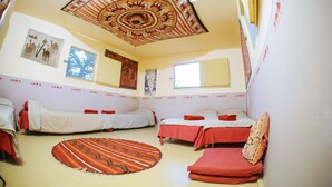 A room with two single beds, a sofa, a patterned rug, and a ceiling with traditional artwork. - Negev Camel Ranch (Dimona)