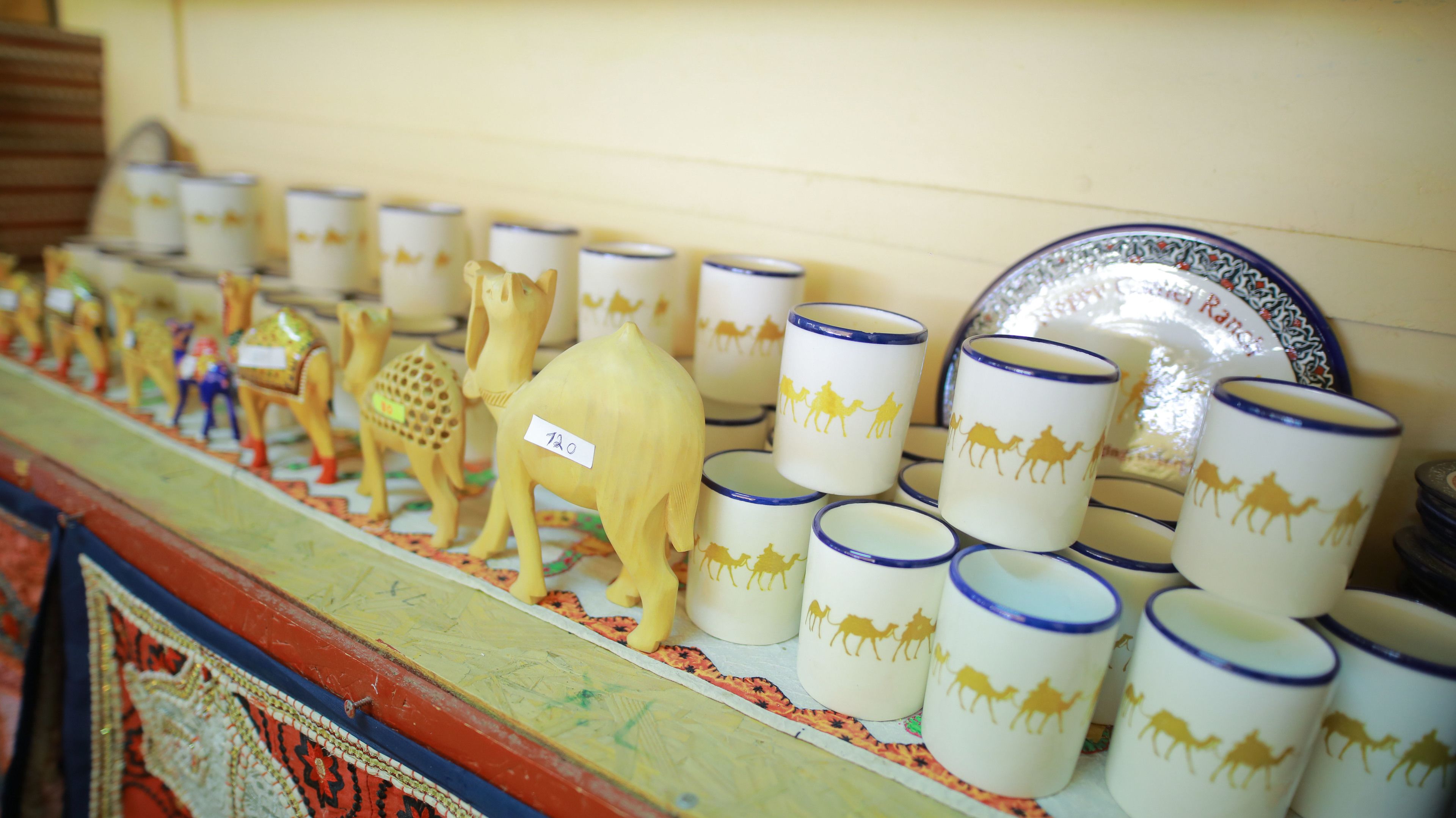 A display of ceramic mugs and figurines on a shelf.