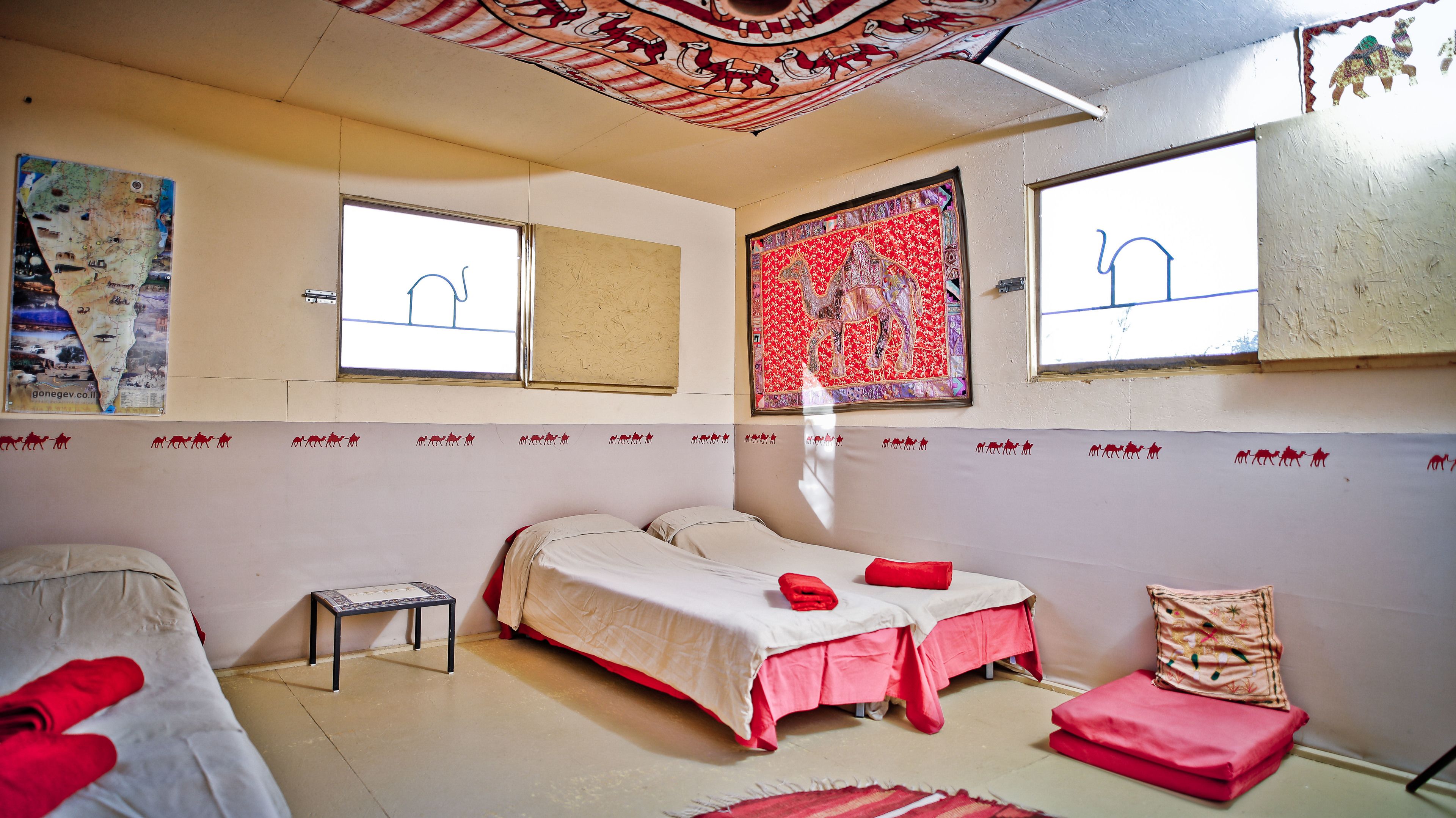 Una habitación con dos camas, una mesita y una ventana.