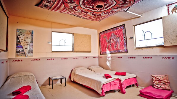 A room with two beds, a small table, and a window.