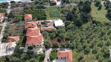Vista aérea de uma área residencial costeira com casas de telhado vermelho, rodeada por vegetação e uma praia.