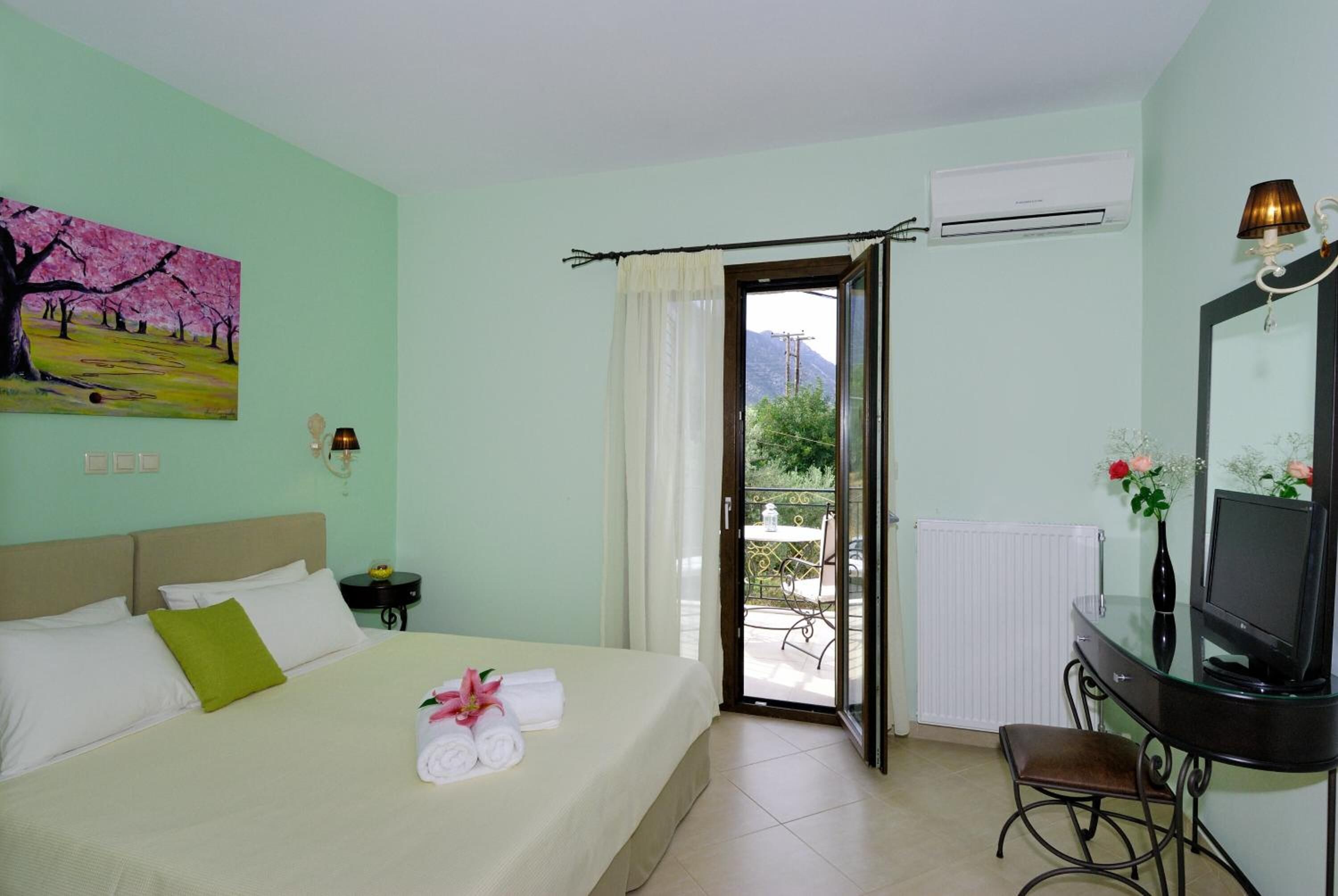 Habitación de hotel con cama, escritorio con televisor, un cuadro en la pared y vistas al exterior.