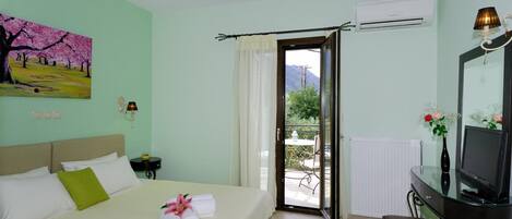 Habitación de hotel con cama, escritorio con televisor, un cuadro en la pared y vistas al exterior.