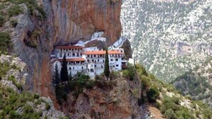 Un hôtel situé au bord d’une falaise, composé de plusieurs bâtiments, dont un bâtiment principal doté d’un toit rouge et de bâtiments plus petits attenants.