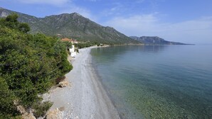 Une route côtière bordée d’une plage, avec des montagnes en arrière-plan.