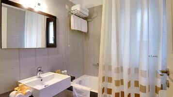 Un baño con lavabo, espejo, toallero y bañera.
