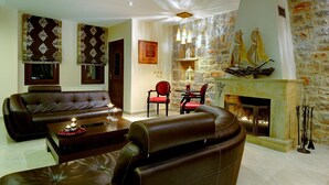 Un salon avec des canapés en cuir, une cheminée et un mur en pierre orné d’une décoration maritime.