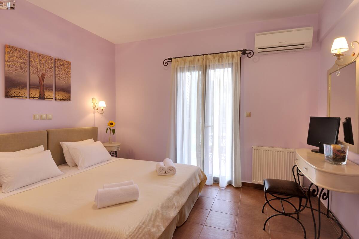 Une chambre d’hôtel avec un lit, un bureau avec un ordinateur, un radiateur et une fenêtre avec des rideaux.