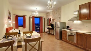 Une cuisine moderne avec des meubles en bois, un réfrigérateur en acier inoxydable et un four encastré. On y trouve également un coin repas avec une table dressée pour deux personnes et un lustre au-dessus.