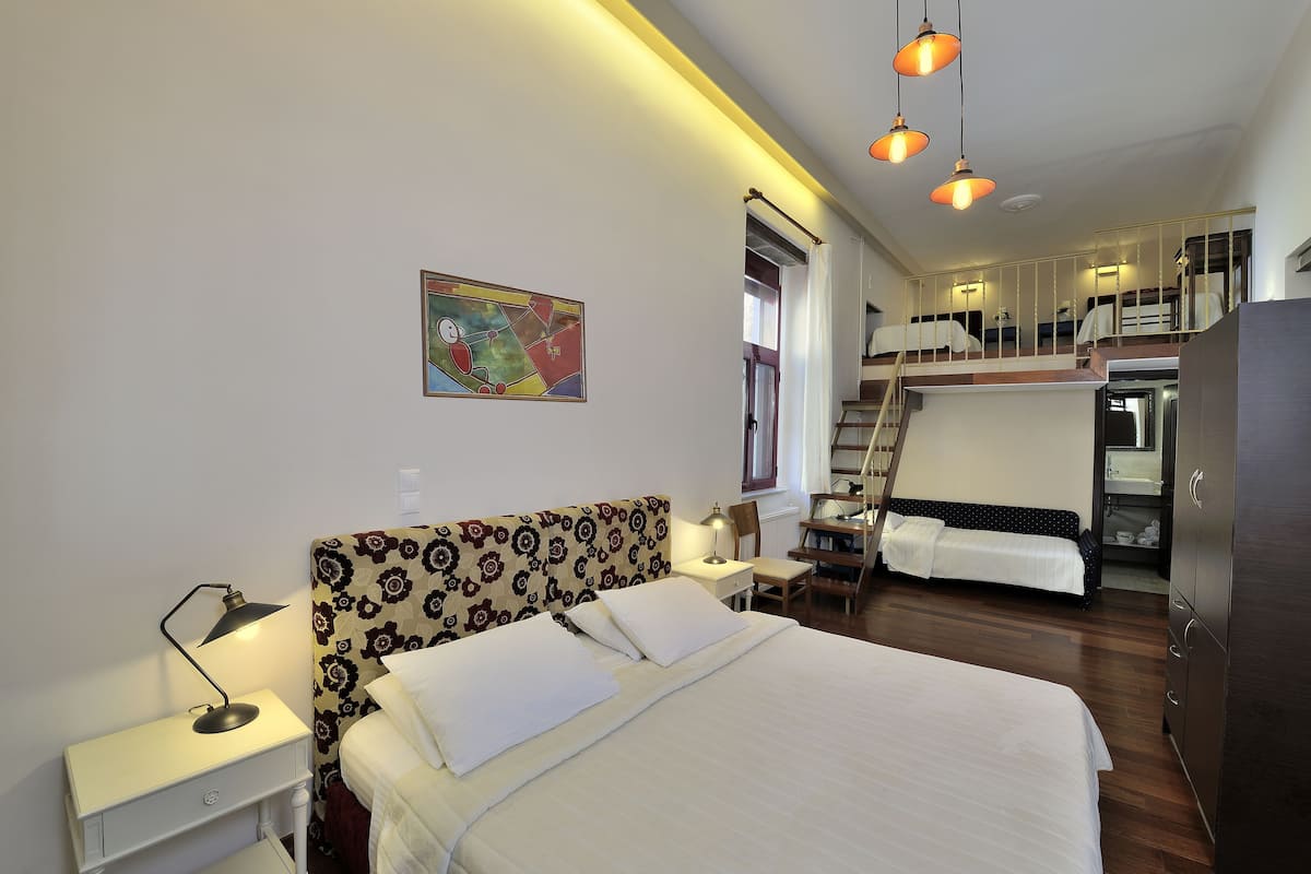 A hotel room with a bed, bedside table, lamp, and a painting on the wall.