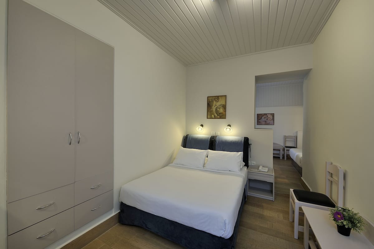 A bedroom with a bed, bedside table, lamp, and wardrobe.