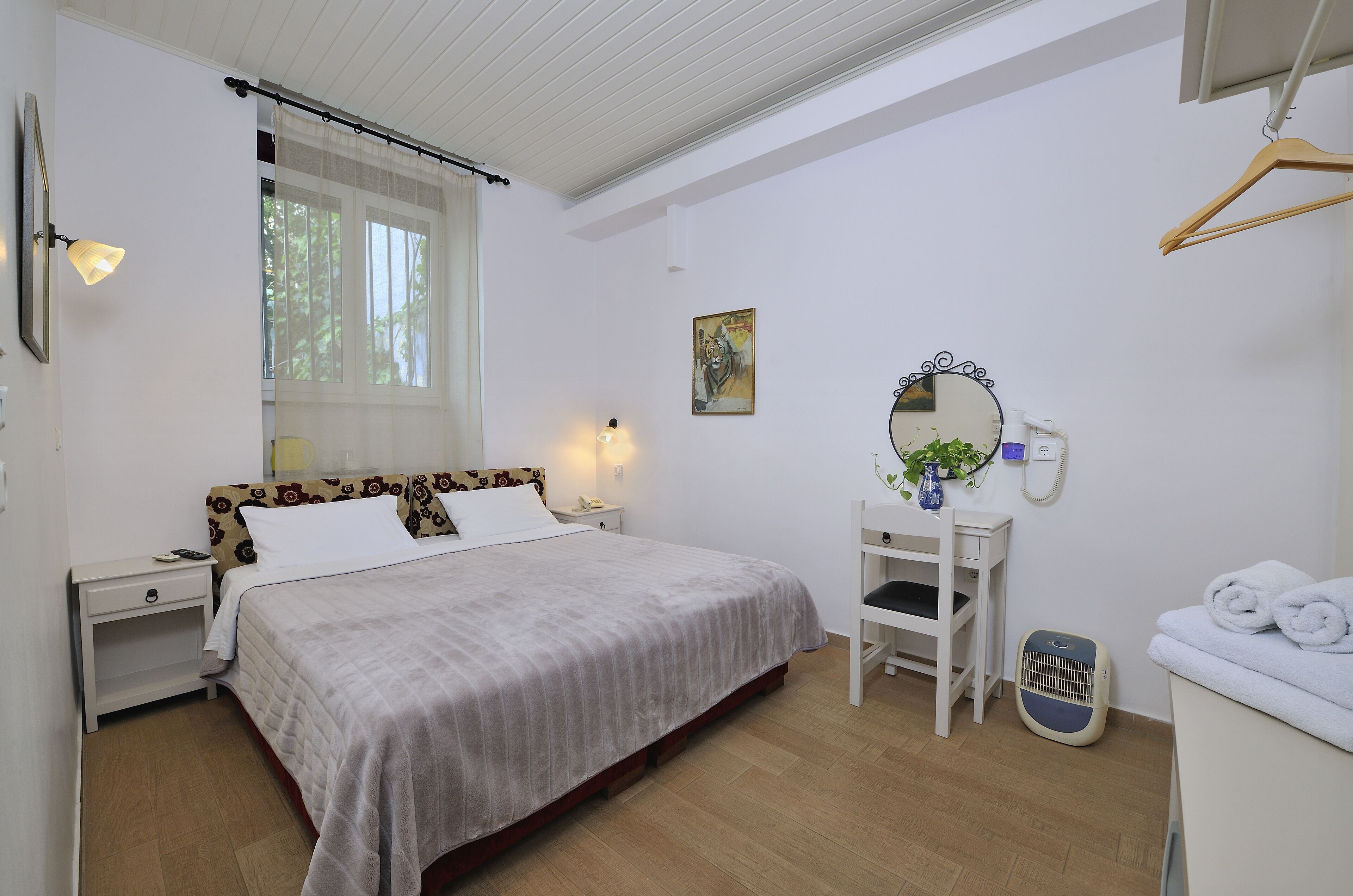 Quarto bem organizado com cama, mesa de cabeceira, abajur e espelho.