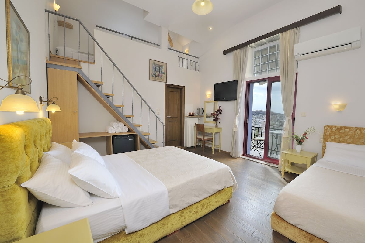 A hotel room with two beds, a staircase, a desk, a chair, and a TV.