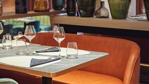 A restaurant interior with a table set for dining, a sofa, and decorative vases. - Hotel Le Clos Rebillotte (Luxeuil-les-Bains)
