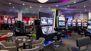 A casino interior with multiple slot machines, bar stools, and tables. - Hotel Le Clos Rebillotte (Luxeuil-les-Bains)