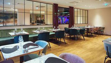 Un restaurante con cabinas y mesas, suelo de madera y ventanas amplias con cortinas.