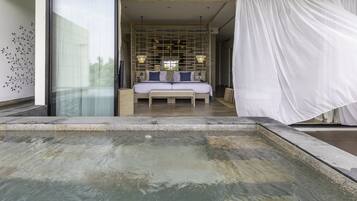 A bedroom with a large bed, bedside tables, and a view of a pool area.