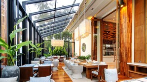 A restaurant with a glass ceiling, wooden flooring, and multiple dining tables and chairs. - Cape Nidhra Hotel Hua Hin (Hua Hin)