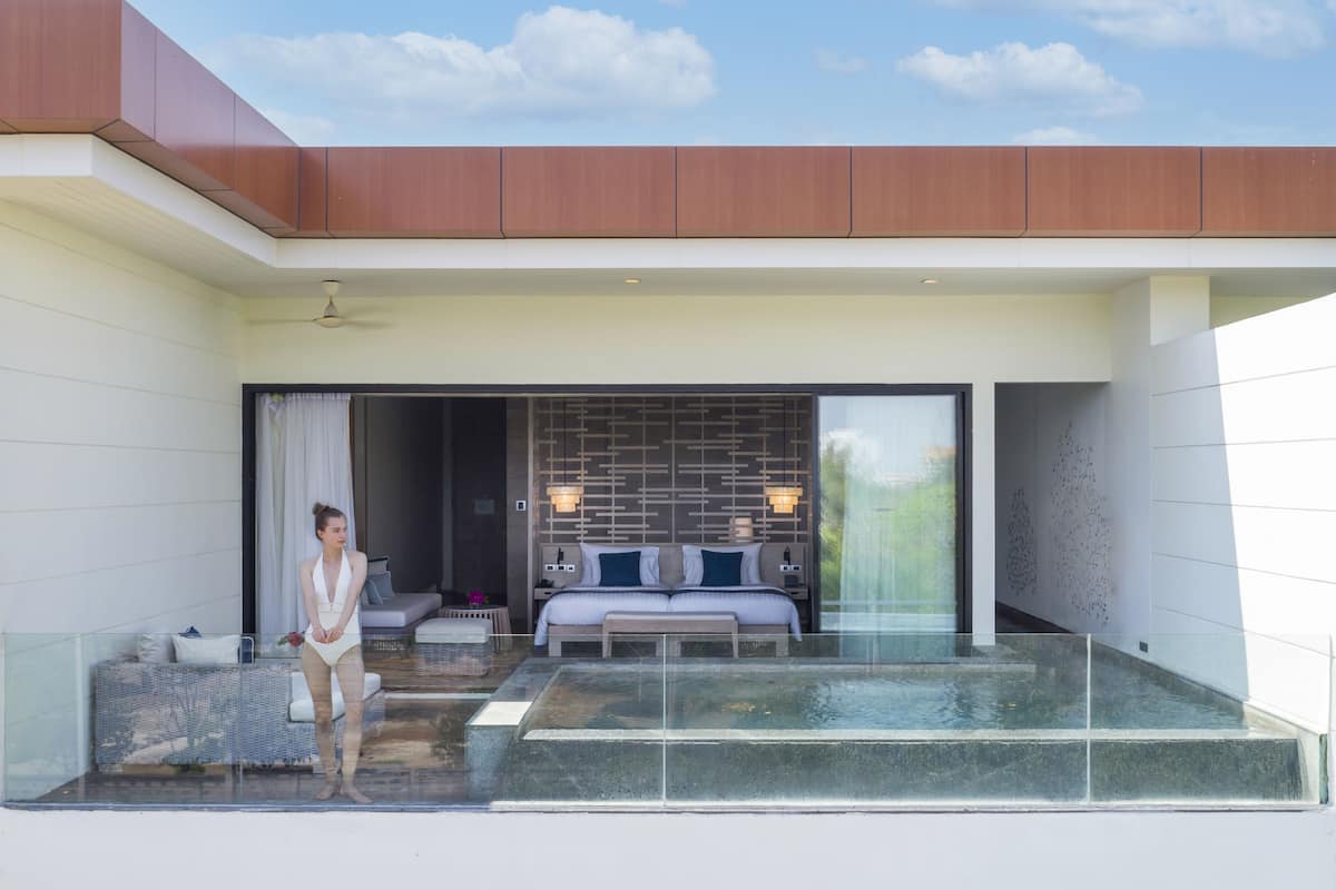 A modern hotel room with a large sliding glass door leading to a private outdoor area with a pool.