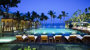 A poolside area with lounge chairs and palm trees, overlooking a body of water. - Cape Nidhra Hotel Hua Hin (Hua Hin)