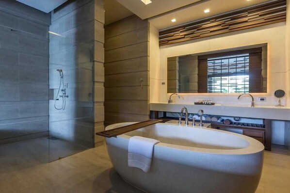 A modern bathroom with a freestanding bathtub, a glass-enclosed shower, and a large mirror above the sink.