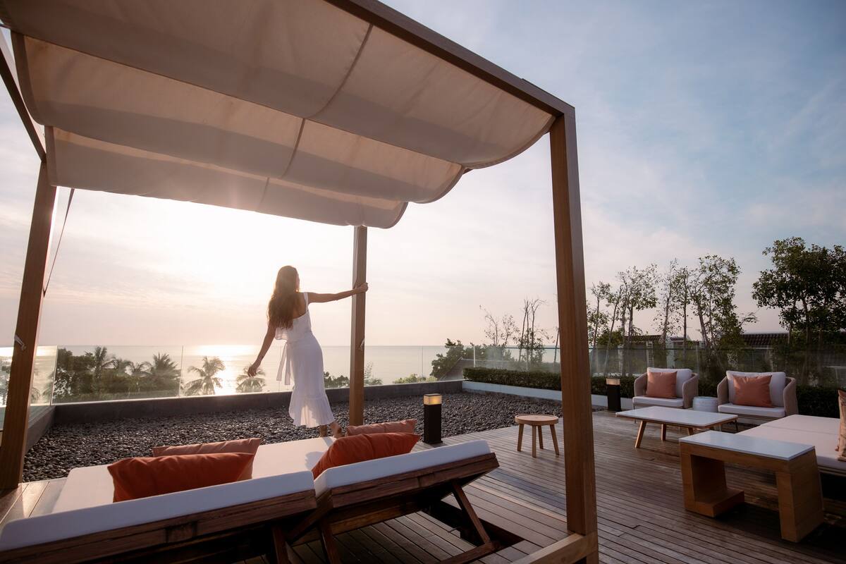 A rooftop terrace with a wooden deck, lounge chairs, and a canopy.