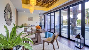 A modern interior with a wooden ceiling, a dining area with a table and chairs, and large windows offering a view of the outdoors. - Cape Nidhra Hotel Hua Hin (Hua Hin)