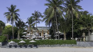 A hotel with a pool area, palm trees, and outdoor seating with umbrellas. - Cape Nidhra Hotel Hua Hin (Hua Hin)