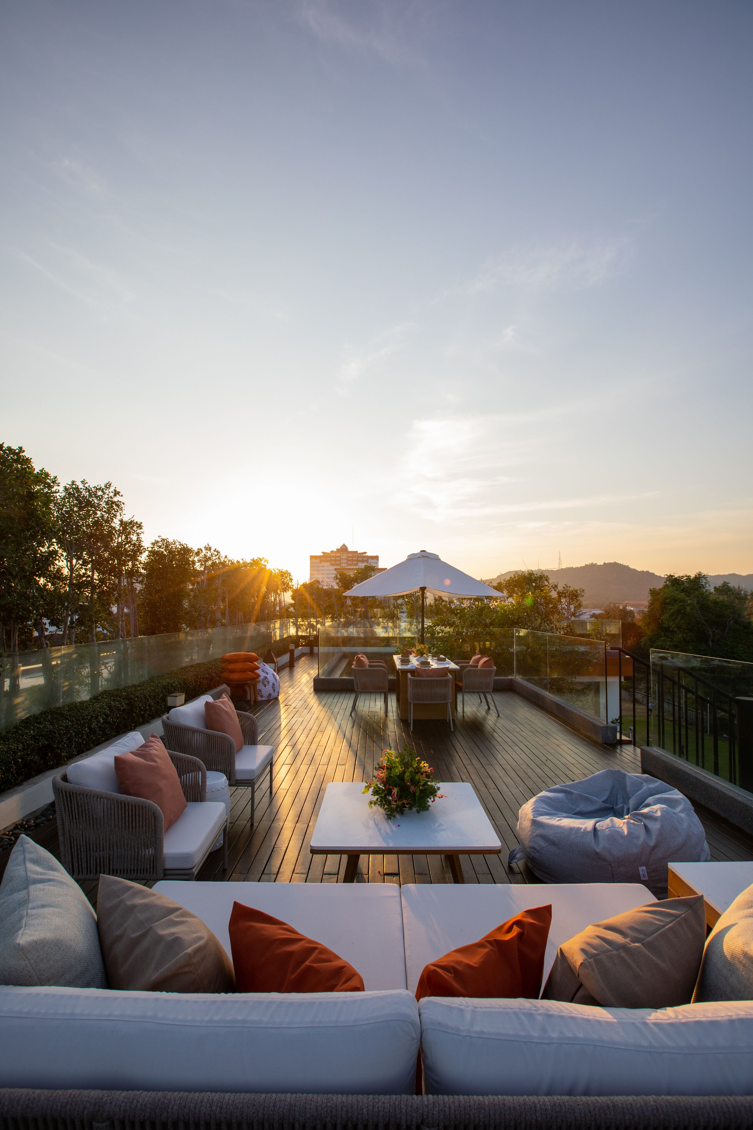 A rooftop terrace with outdoor seating, a table, and a view of the cityscape during sunset.