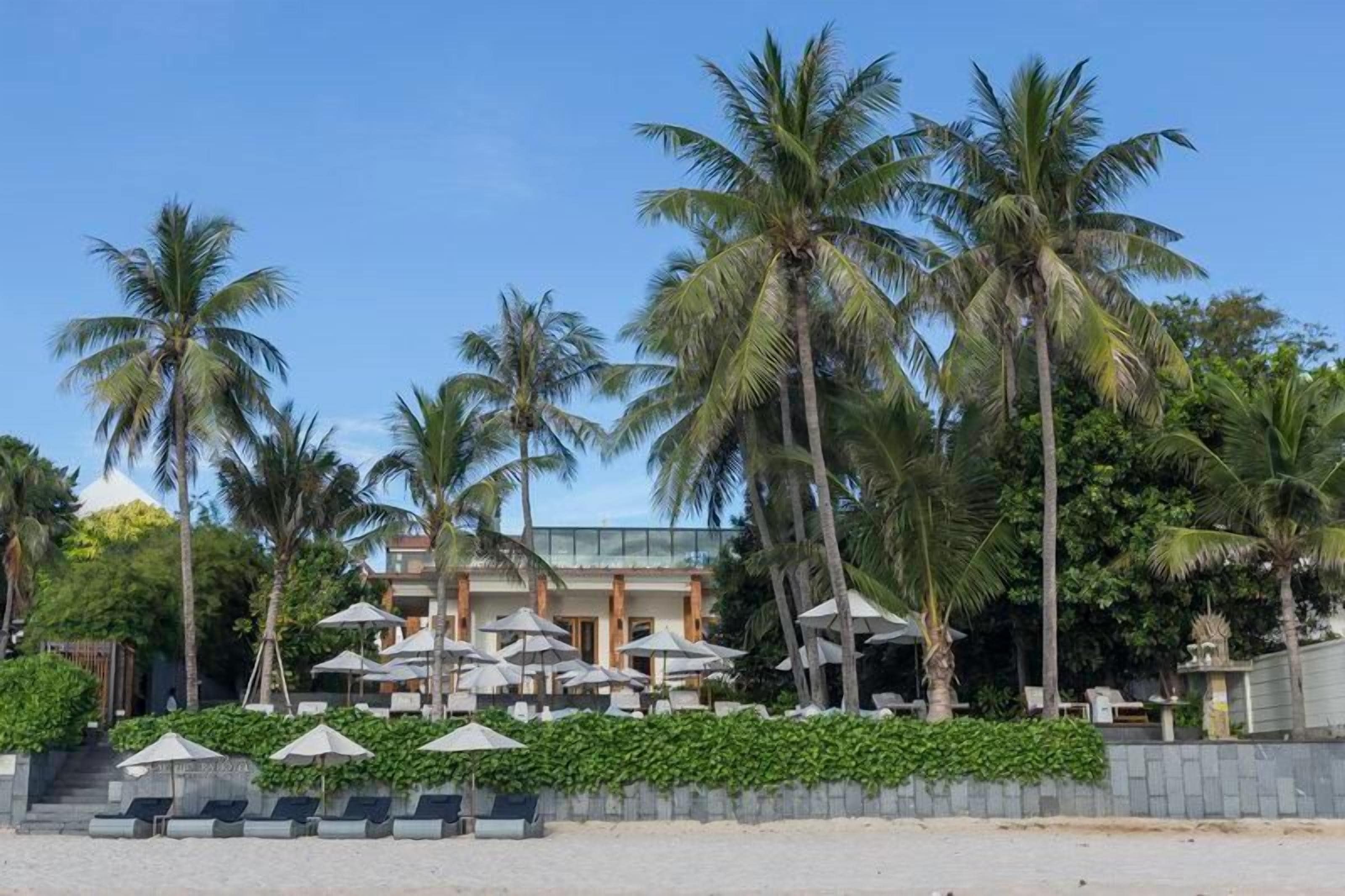 A hotel with a poolside area, palm trees, and outdoor seating.
