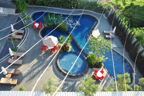 Un área de piscina en la azotea con varias zonas de estar y una fuente central.