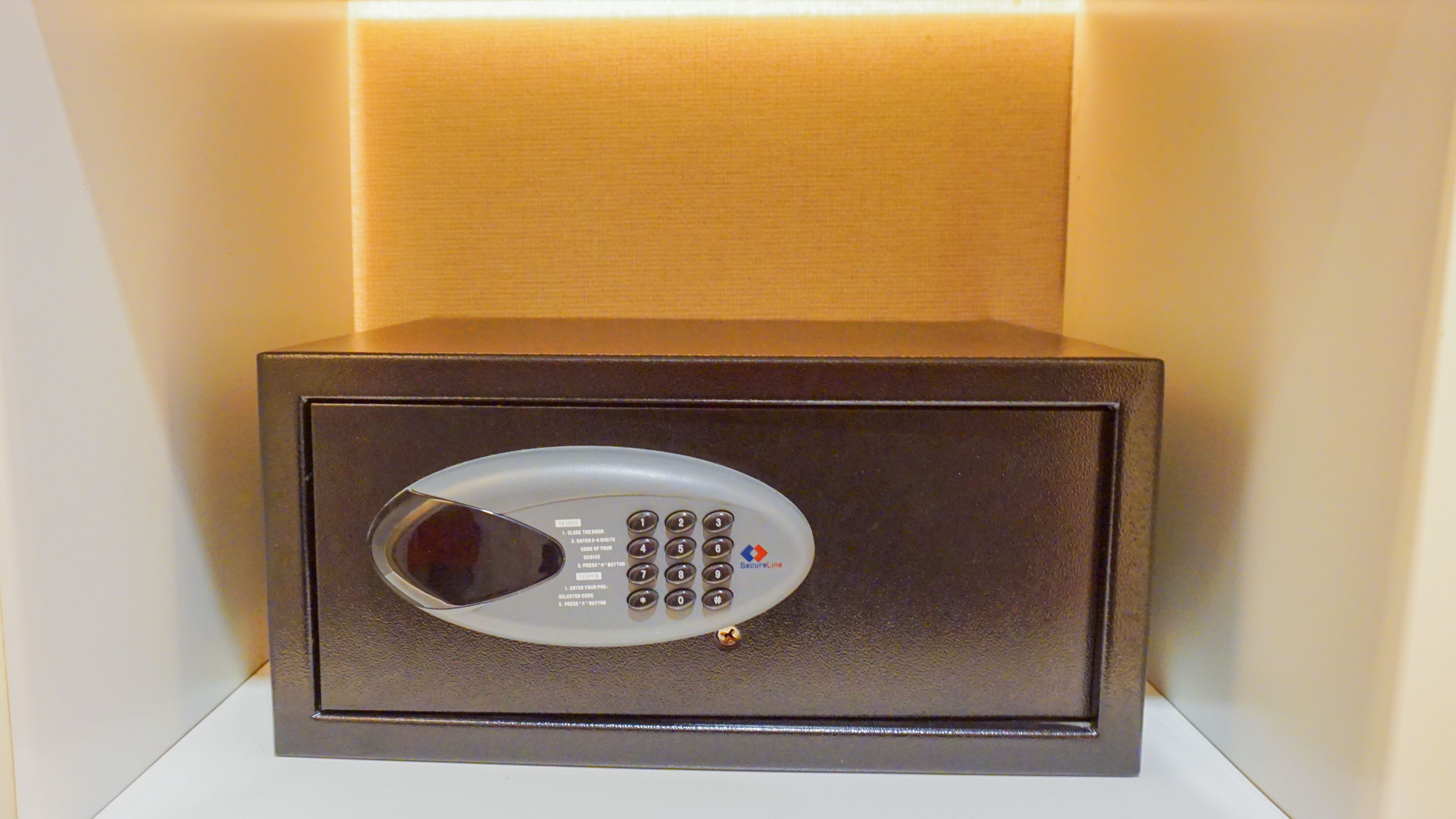 Una caja fuerte segura con cerradura numérica, ubicada en una habitación con pared color crema y piso blanco.