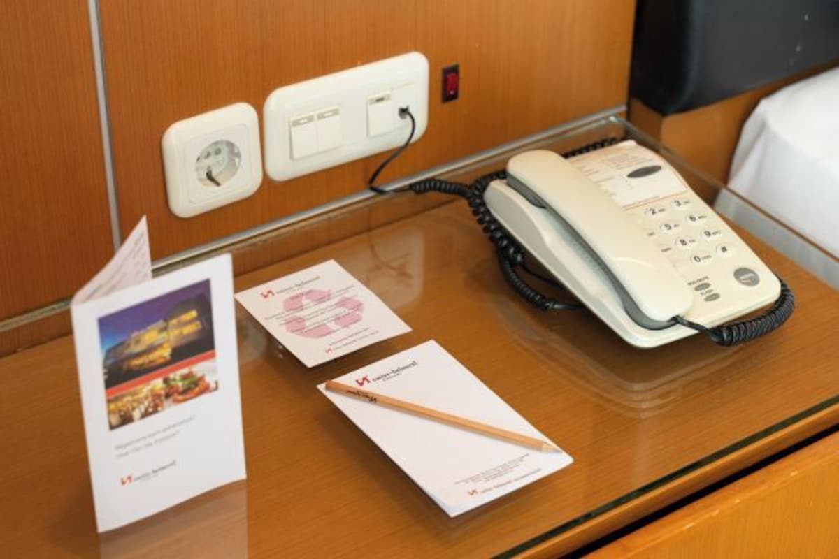 Una habitación de hotel con un escritorio de madera, un teléfono y folletos informativos.