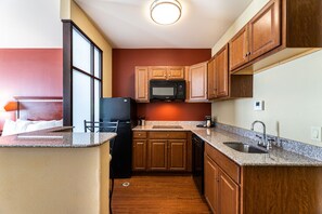 A compact kitchen with wooden cabinets, a microwave, a sink, and a refrigerator.