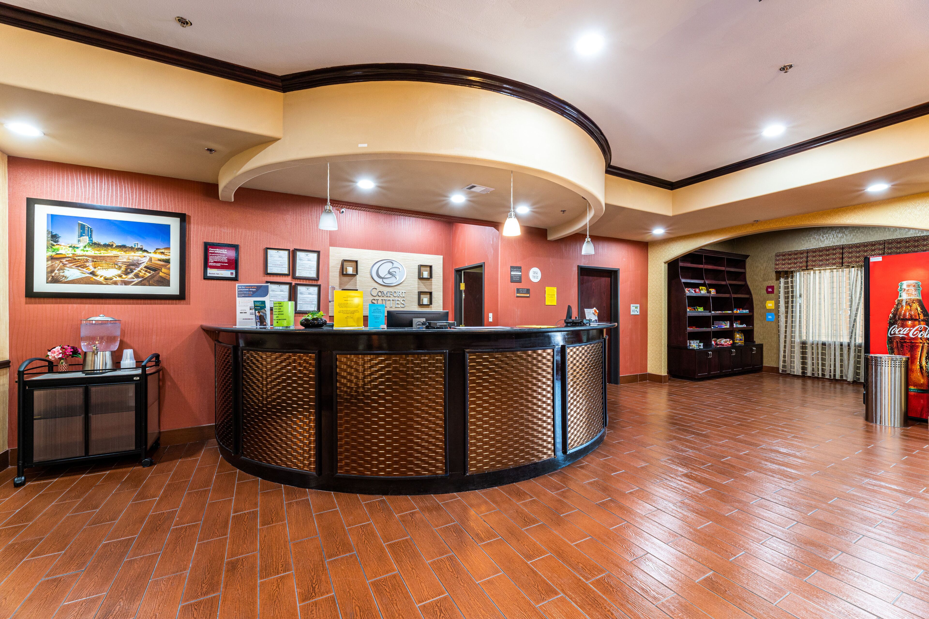 A reception area with a curved counter, framed pictures on the wall, and a Coca-Cola vending machine.