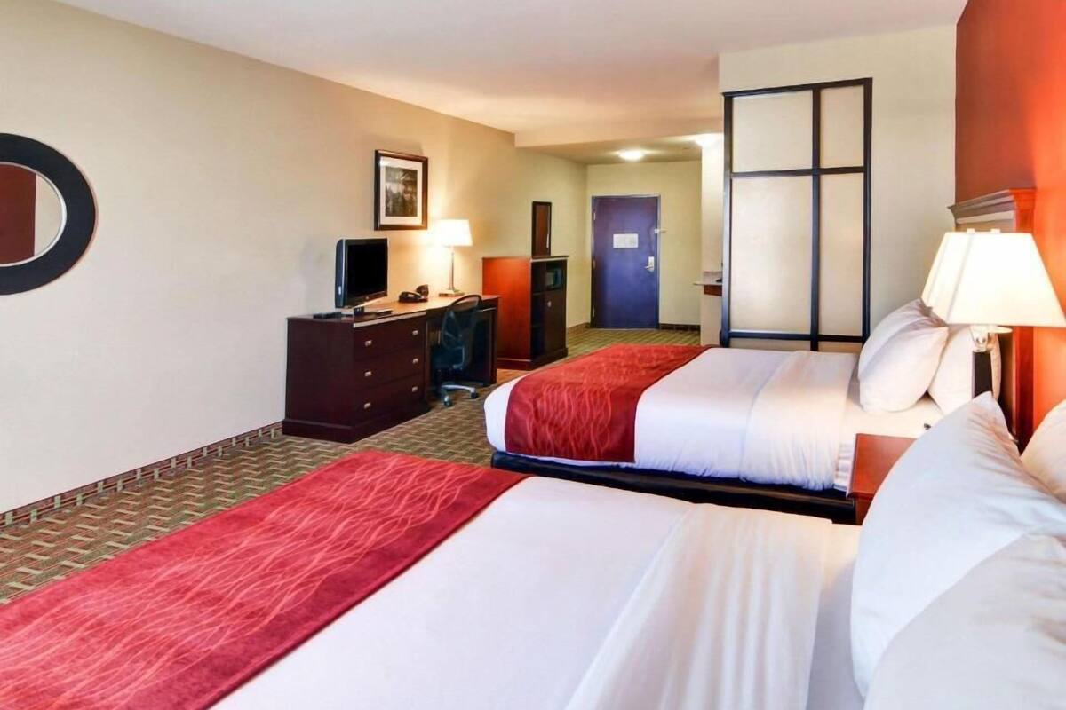 Ett hotellrum med två sängar, ett skrivbord med en dator, en tv och en byrå.