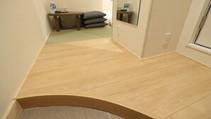 Habitación de hotel con piso de madera, una mesita con almohadas, un espejo y una ventana.
