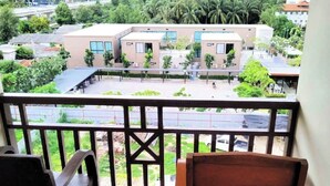 A balcony with a view of a building complex, a wooden chair, and a tiled floor. - LaOr Inn Hua Hin (Hua Hin)