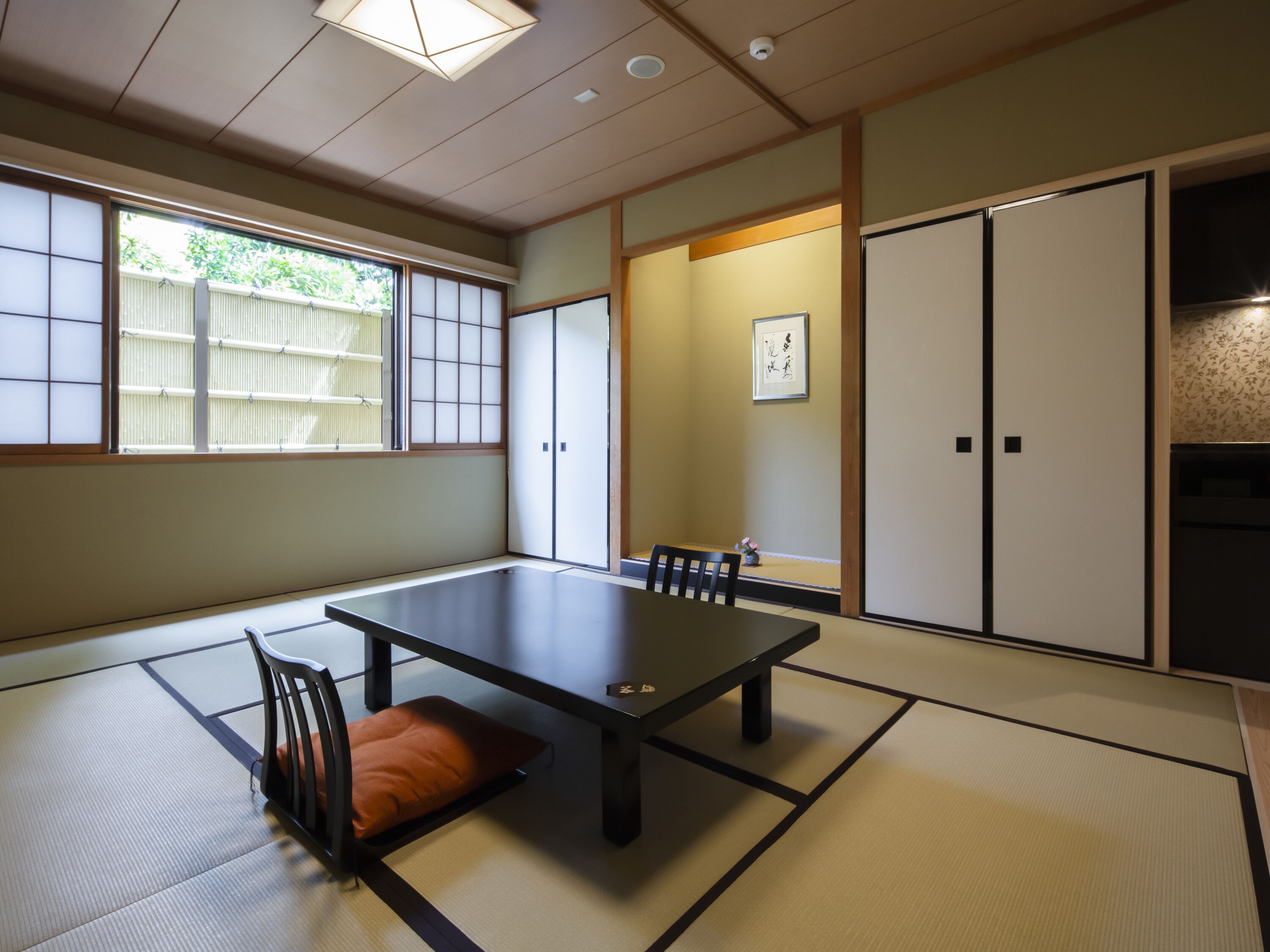 Una habitación tradicional japonesa con suelo de tatami, una mesa baja y puertas correderas.