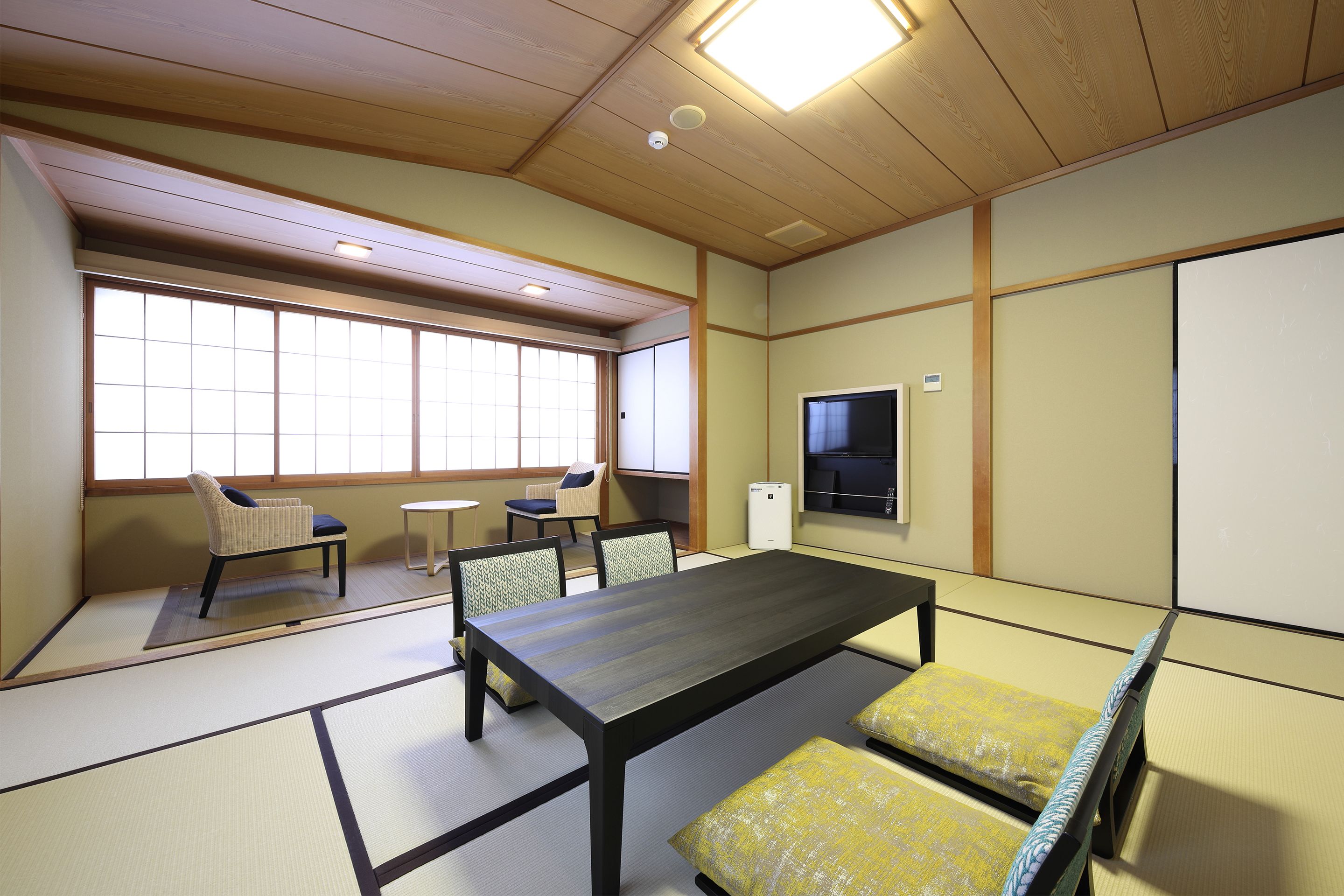 Ein traditioneller Tatami-Raum mit niedrigem Tisch, Kissen und Schiebetüren.