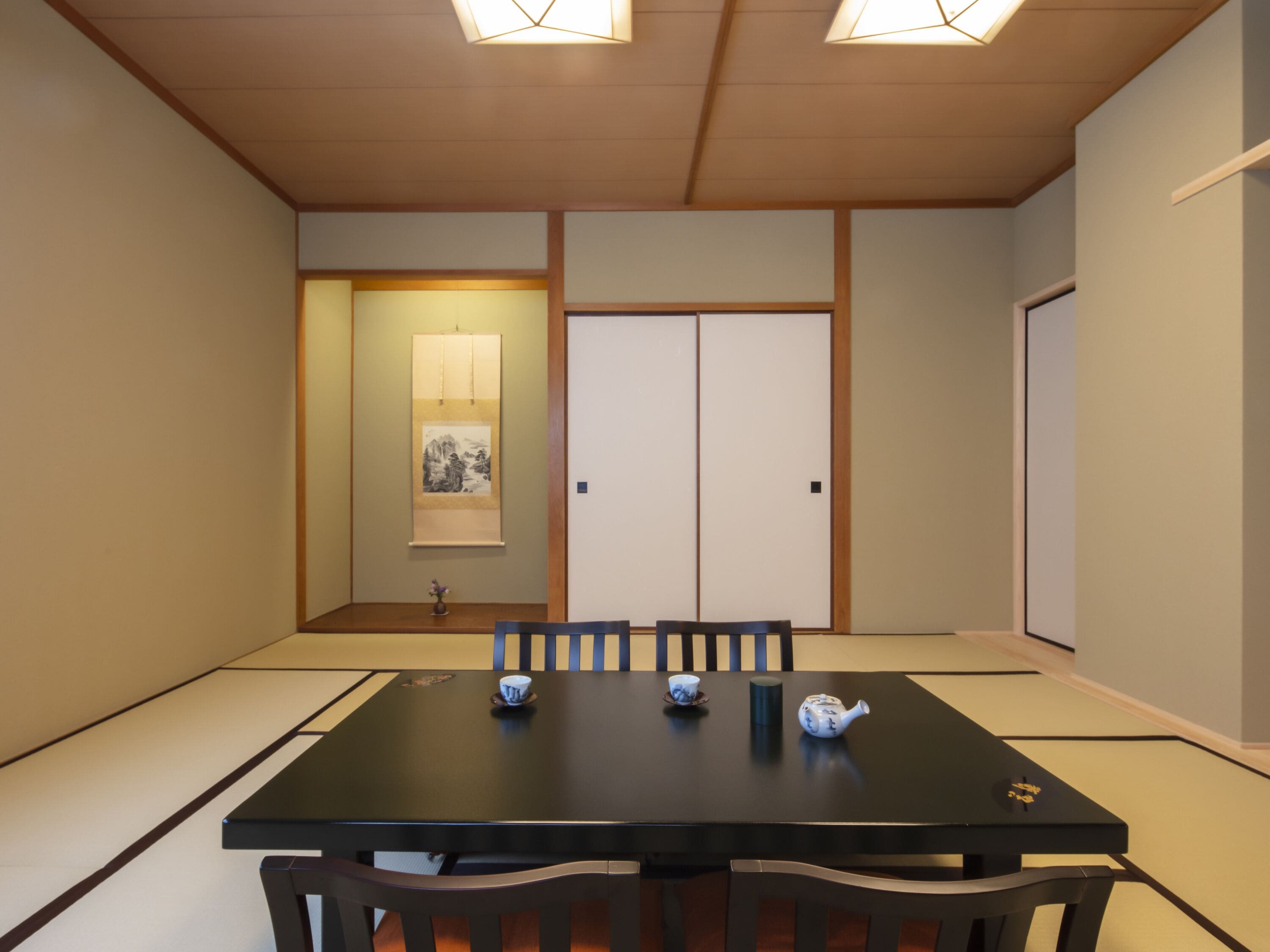 A traditional Japanese-style room with tatami flooring, a low table with a tea set, and sliding doors.