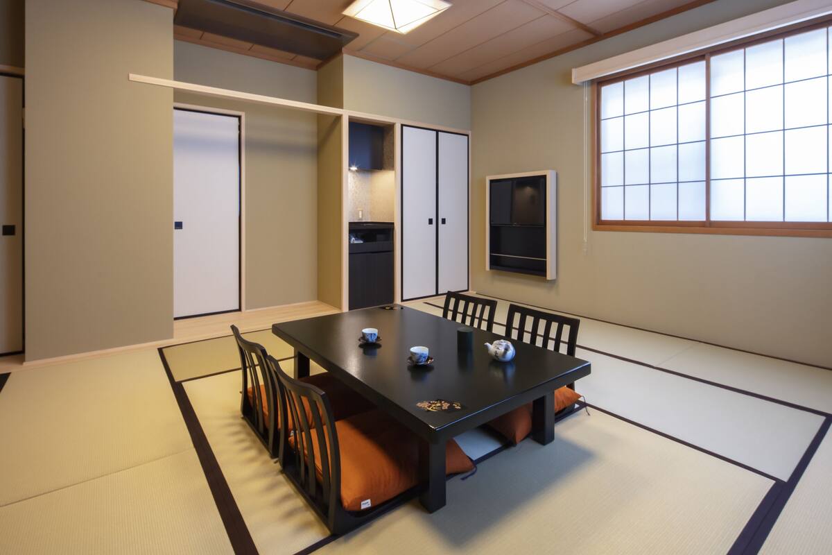 A traditional Japanese-style room with tatami flooring, a low table with cushions, and sliding doors.