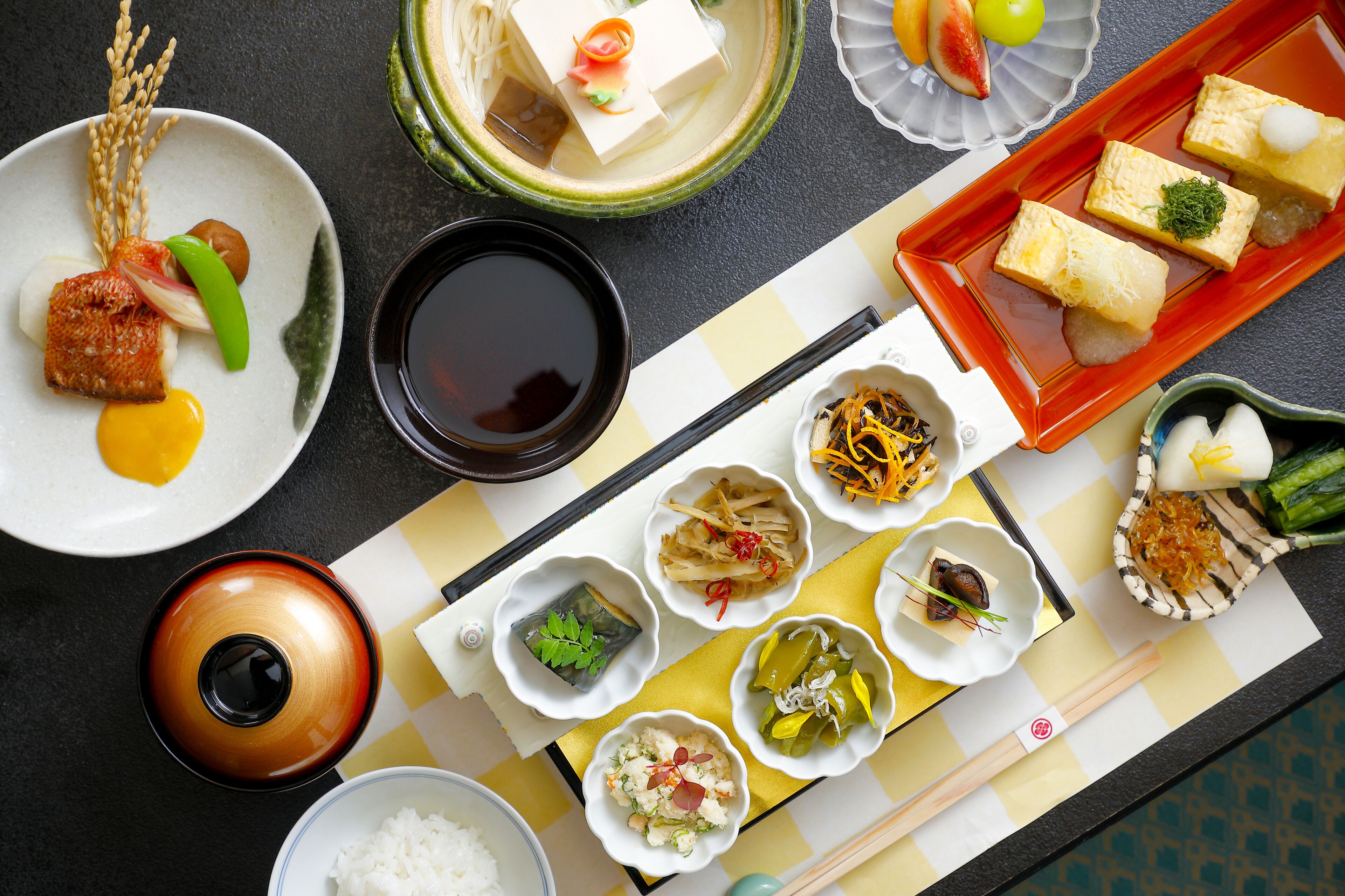 A variety of Japanese dishes arranged on a table with chopsticks, bowls, and plates.