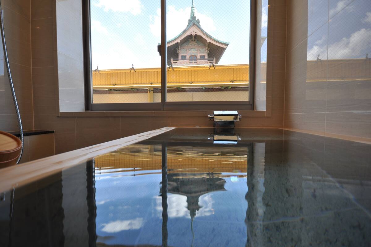A room with a large window, a reflection of a building, and a wooden bench.