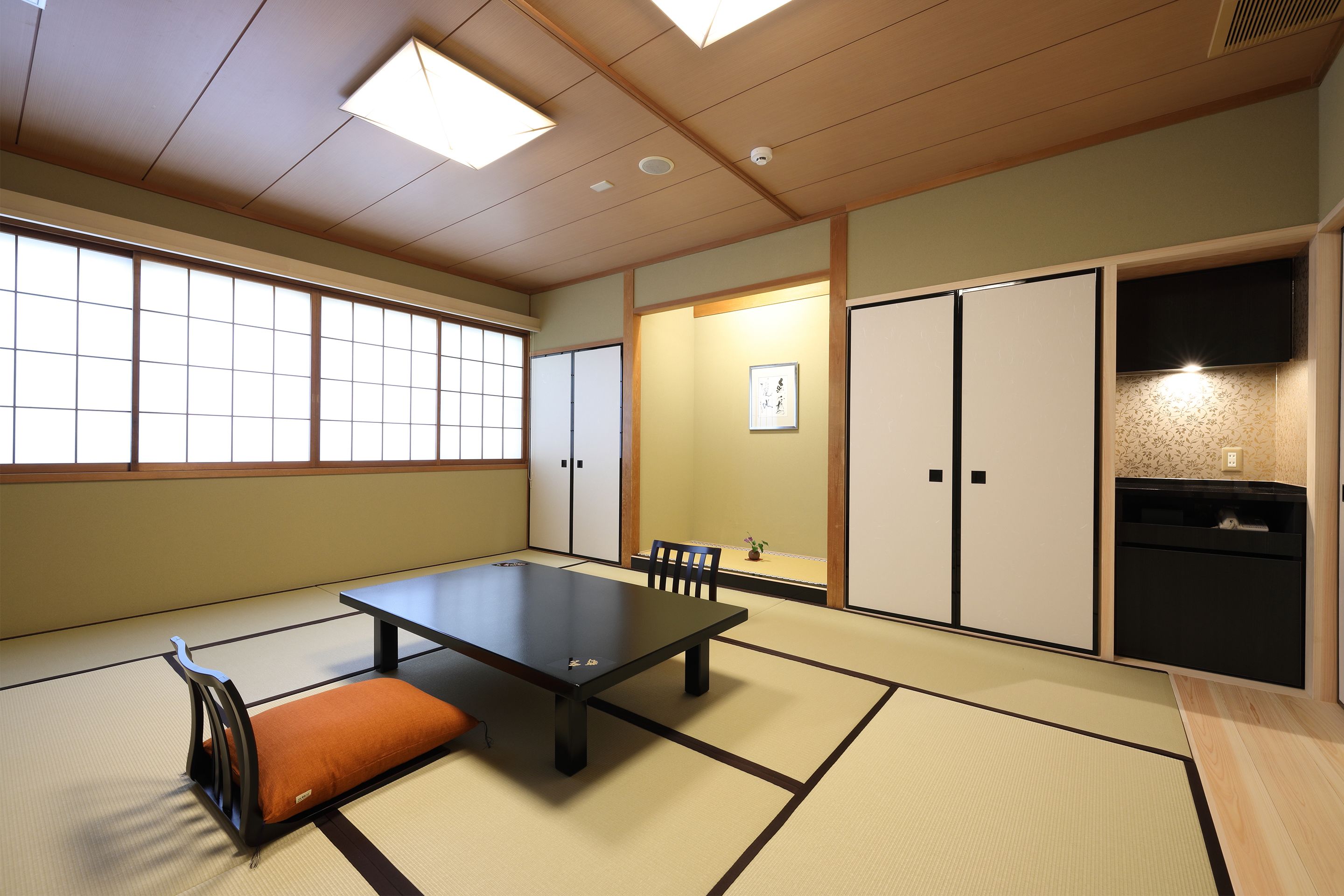 A tatami room with a low table, cushions, and sliding doors.