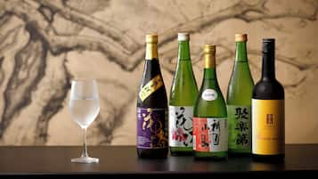 A glass of water and four bottles of Japanese sake on a table.