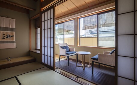 A traditional Japanese room with tatami flooring, shoji screens, and a view of a residential area.