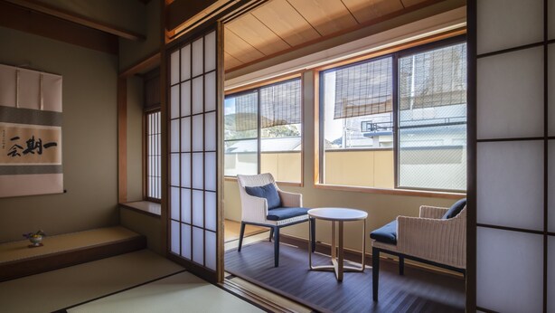 Et traditionelt japansk rum med tatamimåtter, shoji-skærme og udsigt til et boligområde.