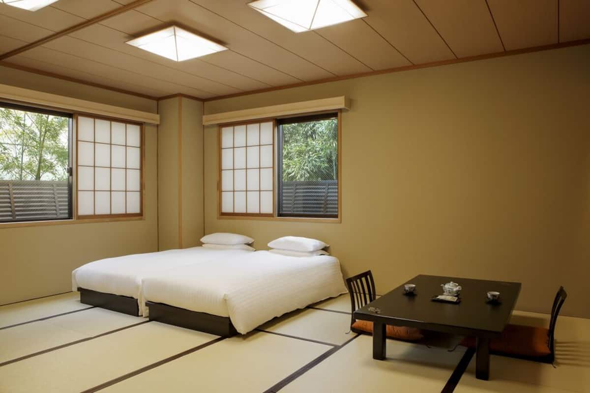 A room with tatami flooring, a bed, a table with tea set, and sliding doors.